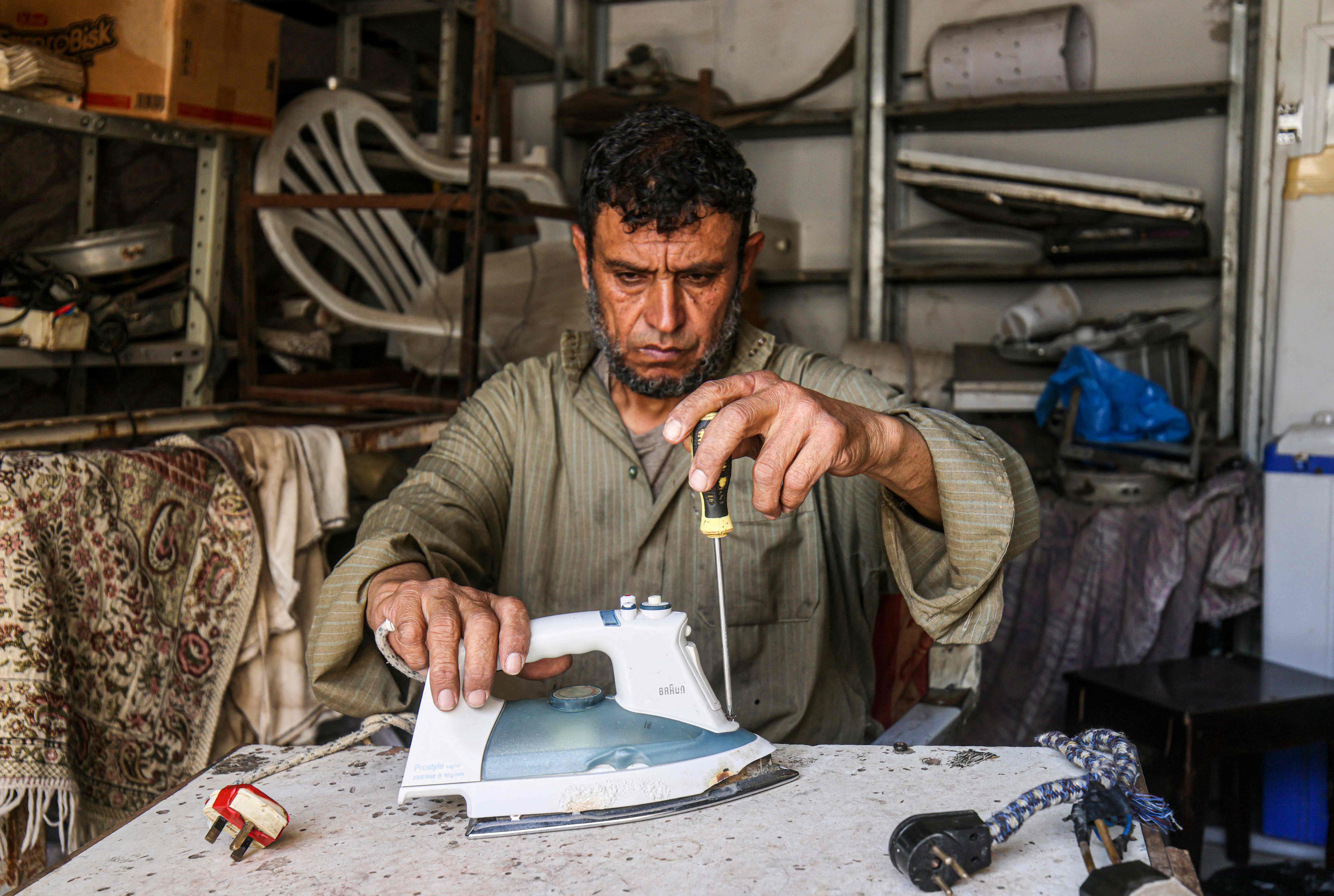 خالد الزعنون يقوم بإصلاح الأجهزة الكهربائية في محله الصغير بمخيم رفح للاجئين .. تصوير: "الفرنسية"